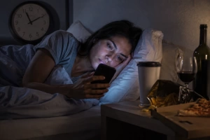 Mujer despierta en la cama usando el celular